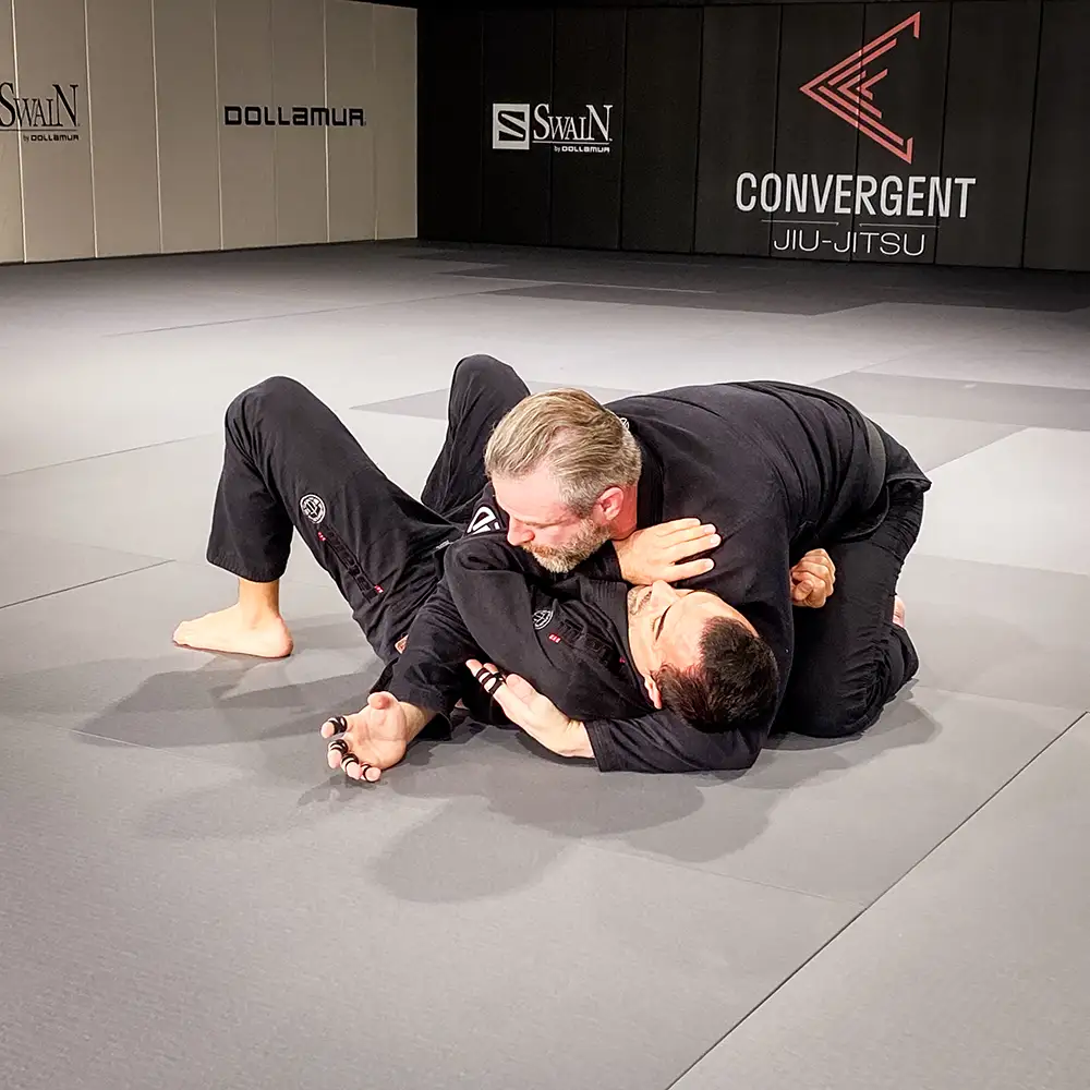 The head instructor of Convergent Jiu-Jitsu demonstrating BJJ technique on a BJJ partner in front of a BJJ class at Convergent Jiu-Jitsu